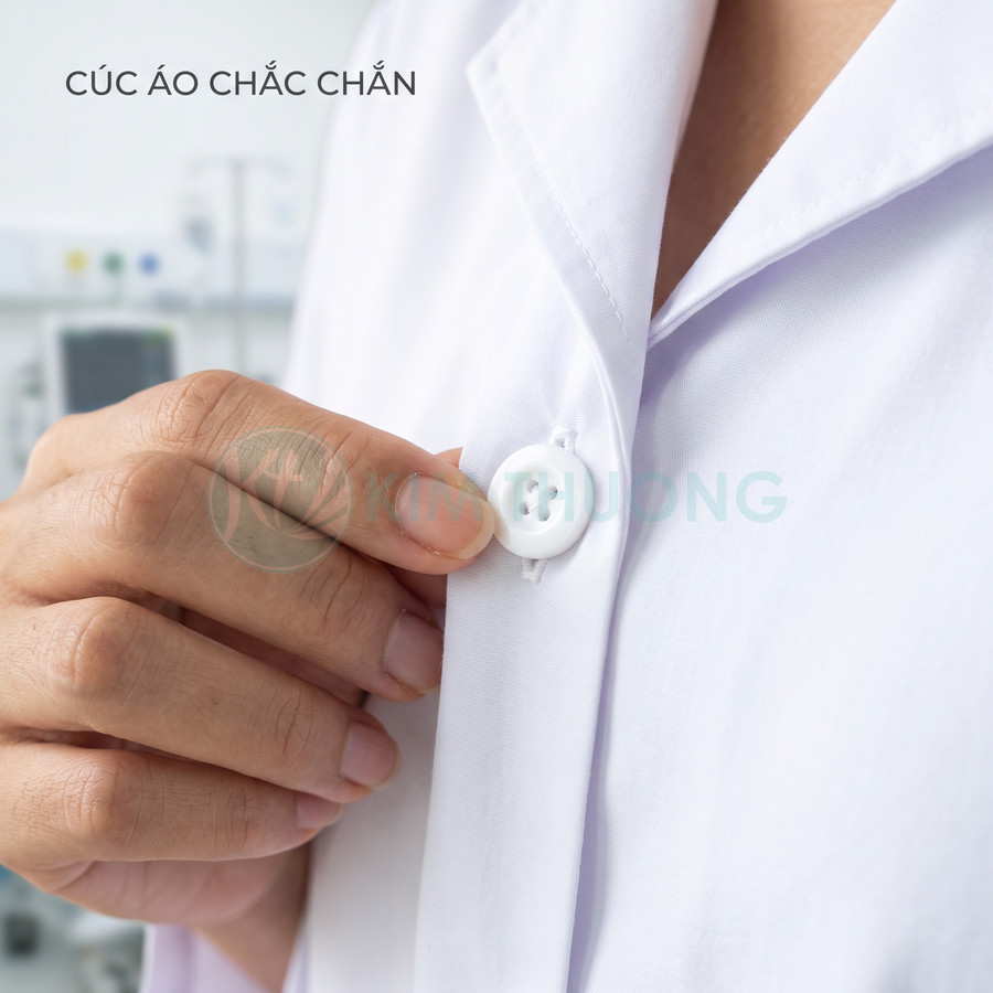 Cận cảnh tay người cài cúc áo blouse trắng chắc chắn trong phòng khám