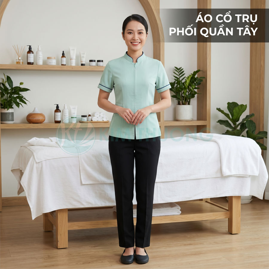 Nhân viên spa mặc áo đồng phục cổ trụ màu xanh mint phối quần tây đen đứng trong phòng trị liệu
