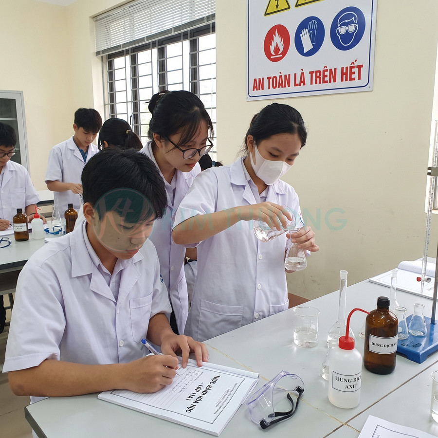 Học sinh thực hành hóa học với cốc thủy tinh, bình tam giác và chai dung dịch trong phòng thí nghiệm