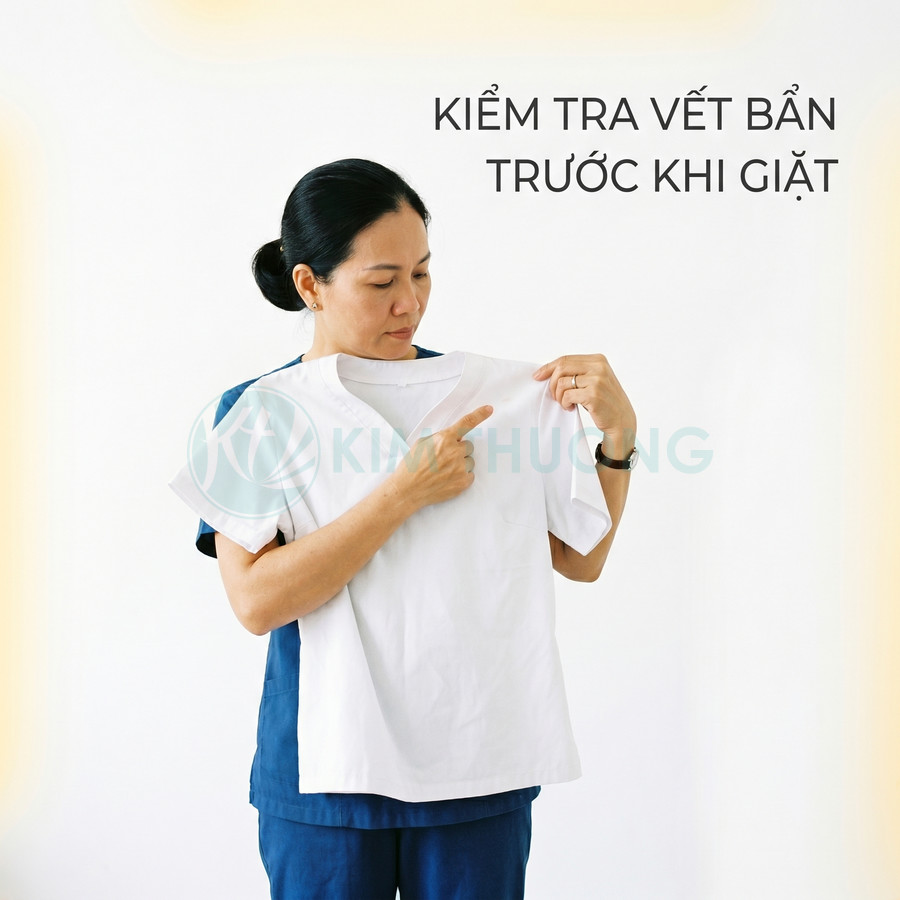Nhân viên giặt ủi kiểm tra vết bẩn trên áo trắng trước khi giặt
