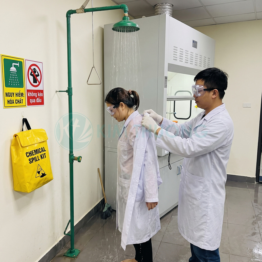 Vòi tắm khẩn cấp màu xanh trong phòng thí nghiệm, bên cạnh túi xử lý hóa chất tràn màu vàng